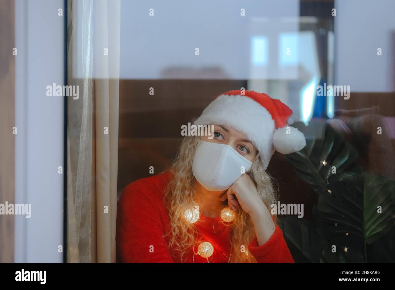 Frau in Weihnachtshut und Champagner feiert Silvester zu Hause Stockfoto