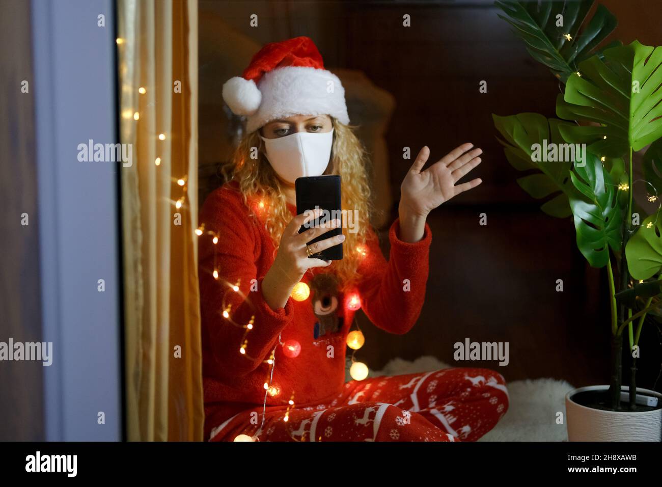 Traurige Frau im Weihnachtsmann feiert Silvester allein zu Hause Stockfoto
