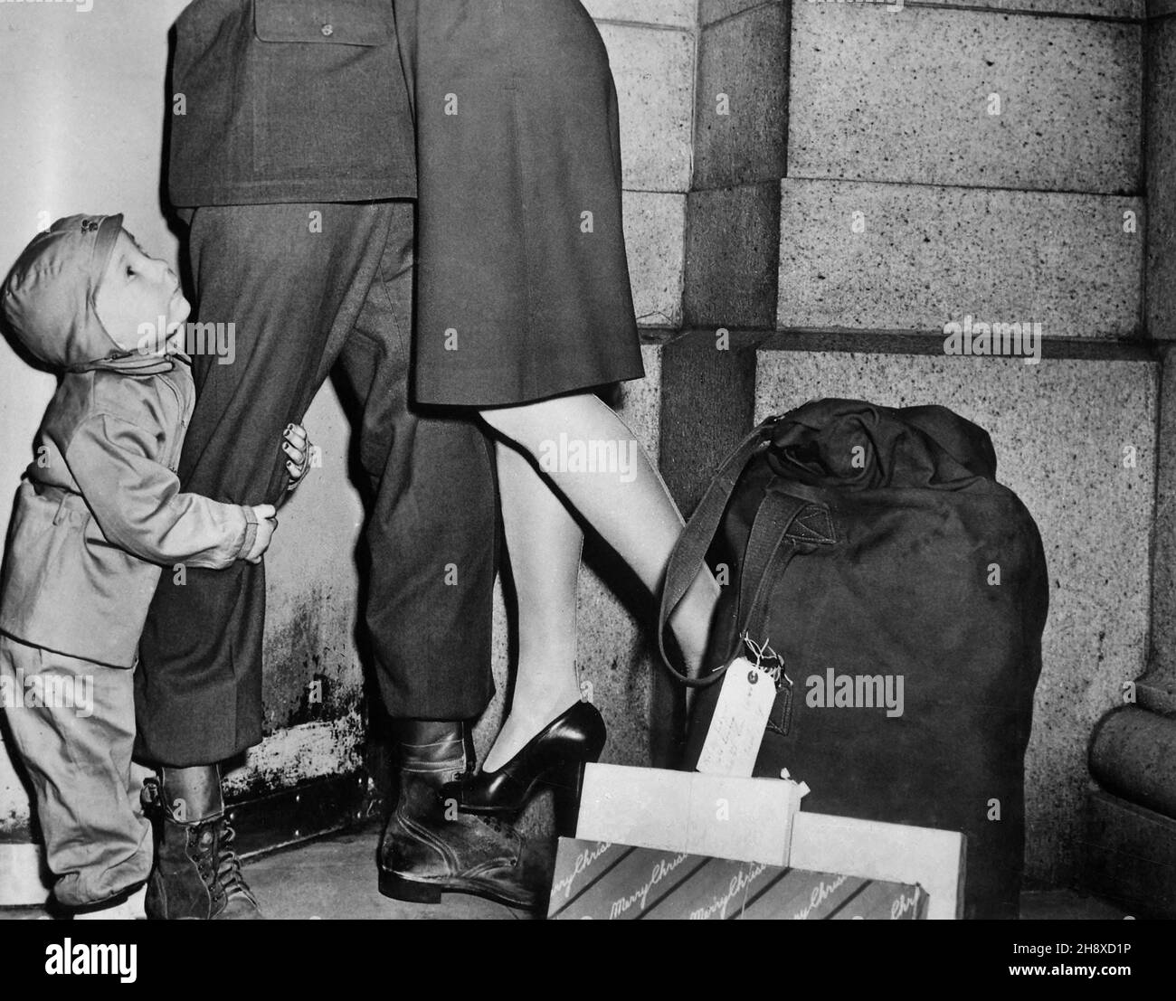 Youngster, der seinen Soldatenvater umklammert und nach oben blickt, während der Soldat seine Frau vom Boden hebt, um ihr „Frohe Weihnachten“ zu wünschen, US Office of war Information, Dezember 1944 Stockfoto
