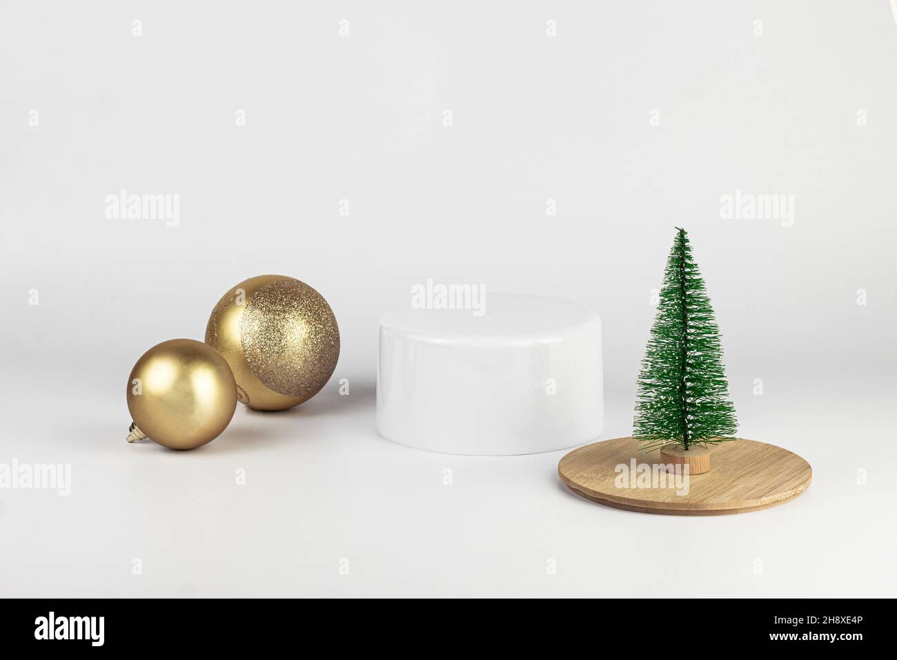 Leere runde weiße und hölzerne Podium. Minimale Weihnachtsszene mit Podium, Weihnachtskugeln und einem kleinen Weihnachtsbaum auf weißem Hintergrund. Neujahr CO Stockfoto