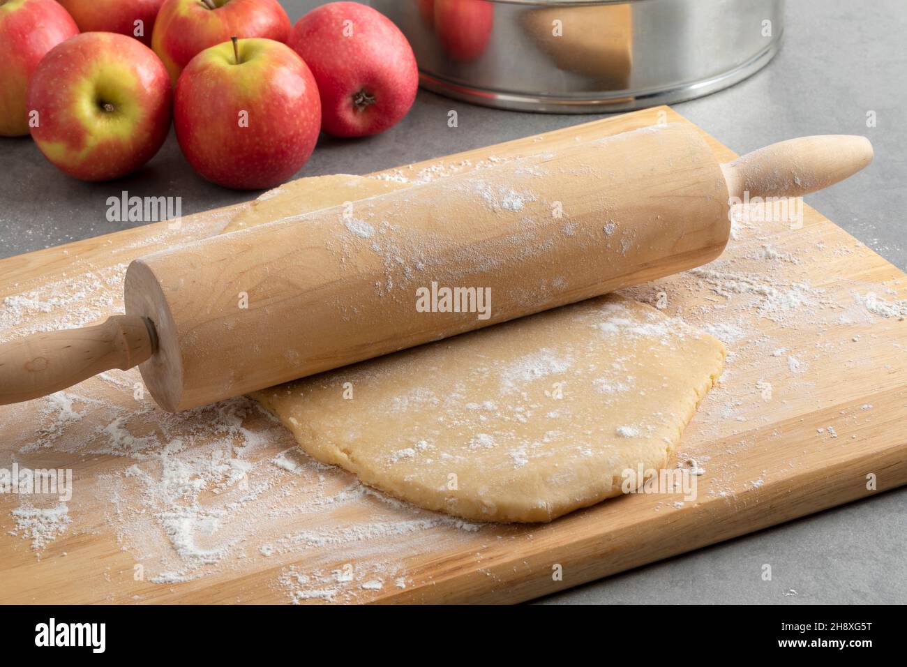 Bereiten Sie frischen Teig mit einem hölzernen Nudelholz und Mehl für das Backen eines Apfelkuchen aus der Nähe Stockfoto