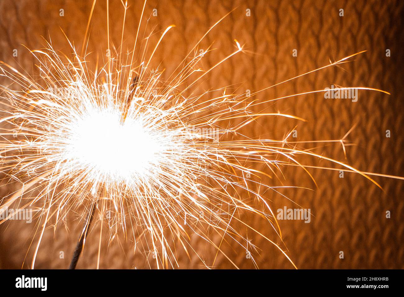 Heller Funkler auf gelbem strukturiertem Hintergrund. Wir feiern Neujahr und Weihnachten. Magische Winterzeit. Selektiver Fokus Stockfoto