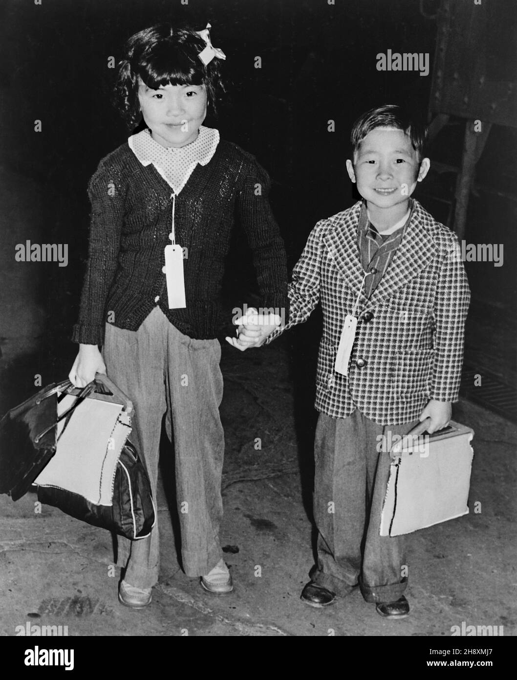 Bruder und Schwester, die zum Umzugszentrum gehen, Identifikationsschilder, die eine Familieneinheit in allen Evakuierungsphasen intakt halten, Hayward, Kalifornien, USA, Dorothea lange, U.S. war Relocation Authority, Mai 1942 Stockfoto