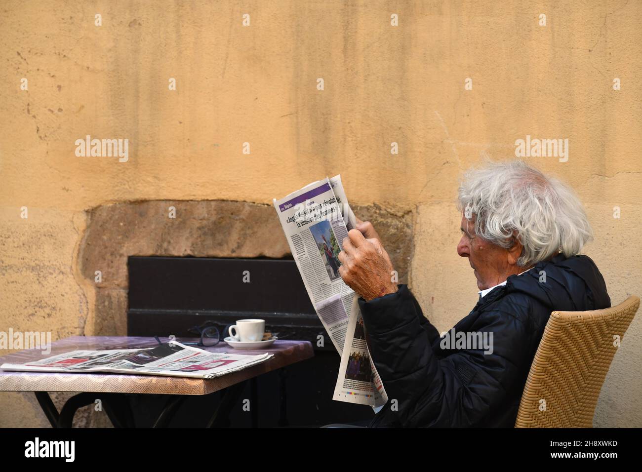 Mann liest Zeitung vor Café Bar Restaurant in Colmar, Frankreich Stockfoto