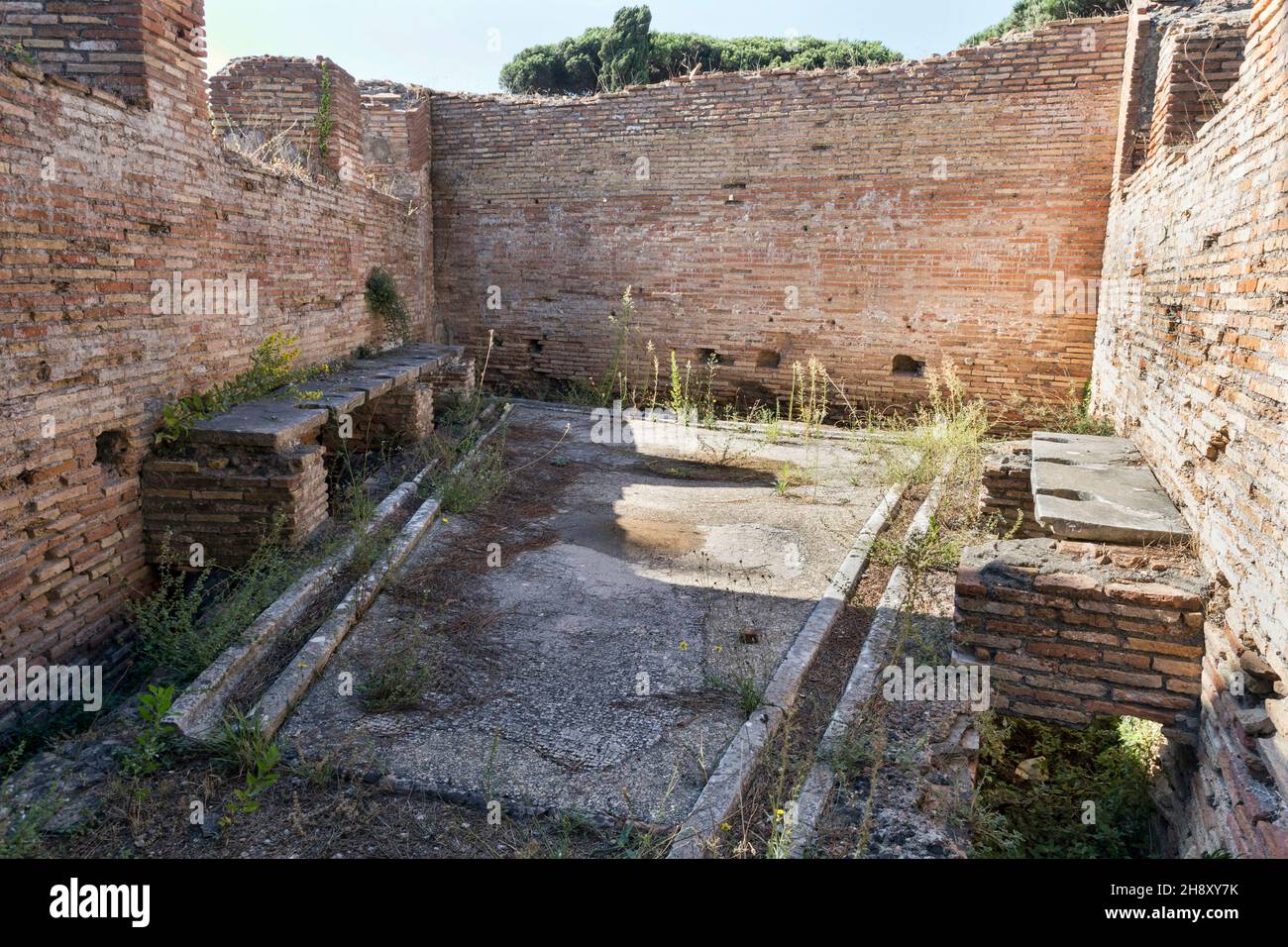 Die gut erhaltenen Überreste eines alten römischen öffentlichen Badezimmers mit Travertin-Sitzen und Toilettenabläufen, unter den Sitzen wurden die Abflüsse ständig cl Stockfoto