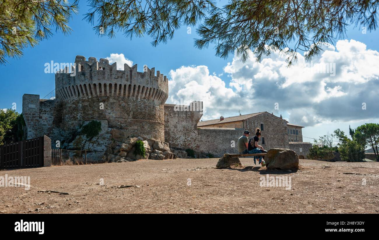 Populonia, Livorno, Italien - 2021, September 18: Ein Paar sitzt auf einer Bank, in der Nähe der befestigten Mauern. Stockfoto