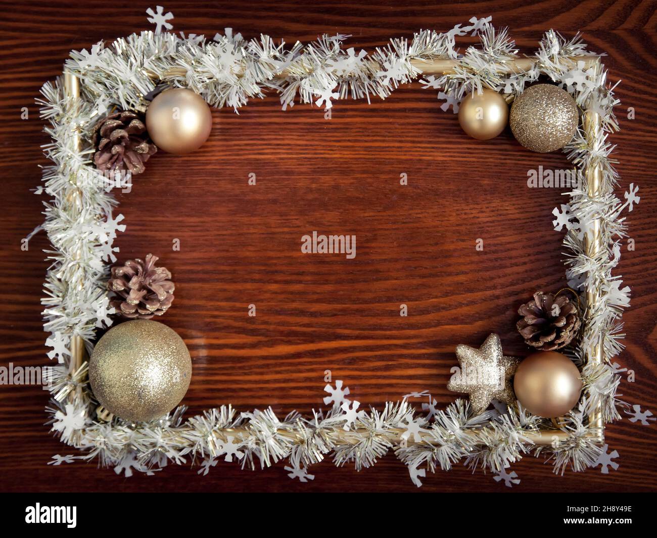 Fotorahmen, goldene Dekorationen auf einem hölzernen Hintergrund. Weihnachten, Winter, Neujahr Konzept. Flach liegend, Draufsicht, Kopierbereich. Weihnachtliche Begrenzung von Kugeln Stockfoto