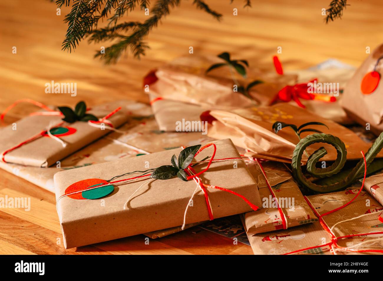 Weihnachten Zusammensetzung.Weihnachten Geschenke mit roten grünen Bändern und Baum Zweig Dekor.Geschenke verpackt in Handwerk recyceltes Papier und Seil Bogen.Winterurlaub Stockfoto