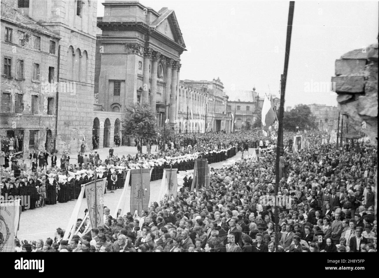 Warszawa, 1946-06-20. Procesja w uroczystoœæ Bo¿Ego Cia³a ulicami zniszczonego miasta. Straty materialne poniesione przez Warszawê w wyniku dzia³añ II wojny œwiatowej zosta³y oszacowane na sumê 45 mld 300 mln dolarów. NZ. t³umy mieszkañców œledz¹ z uwag¹ przebieg œwiêta. W ie doczne od lewej: mury kamienicy Camponiego (obecnie nie istnieje), dzwonnica i koœció³ akademicki pw. œwiêtej Anny. pp PAP/Jerzy Baranowski Warschau, 20. Juni 1946. Eine Prozession am Fronleichnam-Tag auf den Straßen der zerstörten Stadt. Die finanziellen Verluste Warschaus im Jahr WW2 wurden auf 45 Milliarden 300 Mio. geschätzt Stockfoto