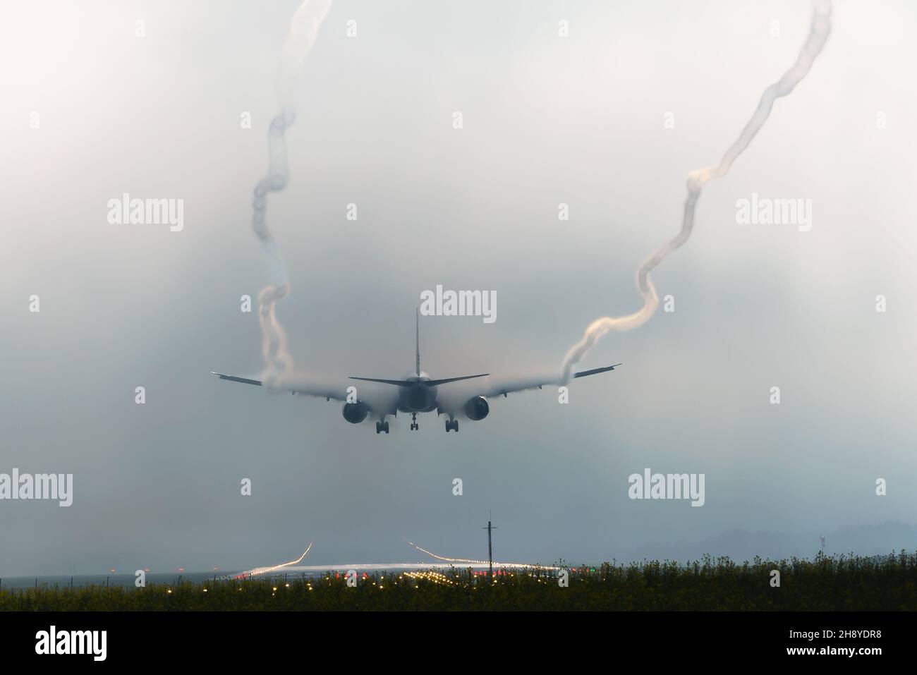 Die Flugzeuge landen mit schlechter Sicht auf der Start- und Landebahn des Flughafens Zürich und hinterlassen Flügelwirbel. Luftwirbel aufgrund von feuchtem Wetter und Kondensstreifen. Stockfoto