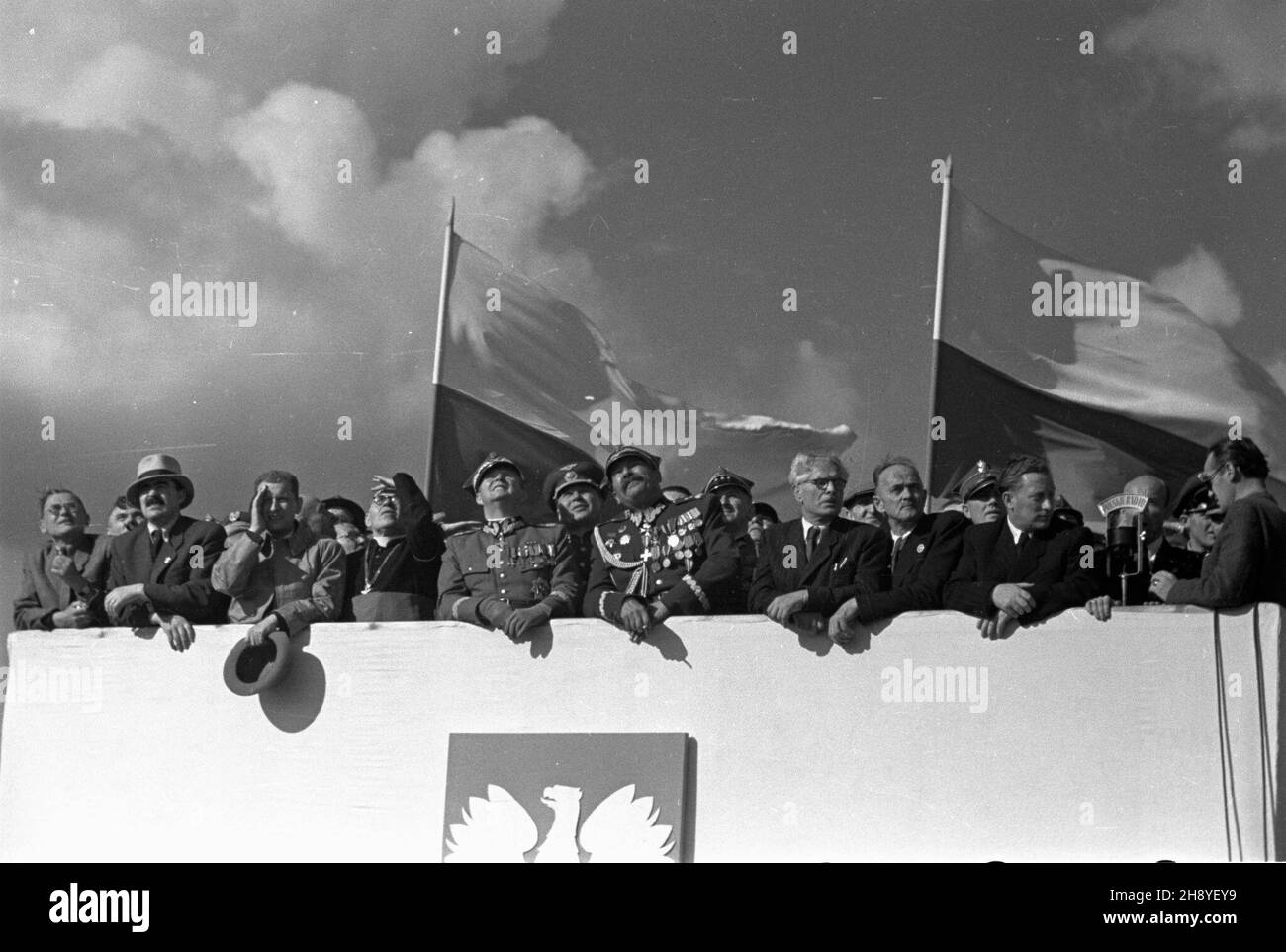 Bydgoszcz, 1946-09-01. Œwiêto Lotnictka Polskiego zbieg³o siê z zakoñczeniem obchodów 600 lecia istnienia Bydgoszczy. Zorganizowane z rozmachem podniebne pokazy zgromadzi³y ok. 100 tys. widzów. NZ. na trybunie honorowej obserwuj¹ samolotowe ewolucje m.in.: Minister lasów Stanis³aw Tkaczow (2L), Minister informacji i propagandy Stefan Matuszewski (3L), marsza³ek Micha³ Rola-¯ymierski (5L). mw PAP Bydgoszcz, 1. September 1946. Der Tag der polnischen Luftfahrt fiel mit dem Abschluss der Feierlichkeiten zum 600th-jährigen Bestehen von Bydgoszcz zusammen. Eine ähnliche Flugshow zog etwa 100.000 Zuschauer an. Im Stockfoto