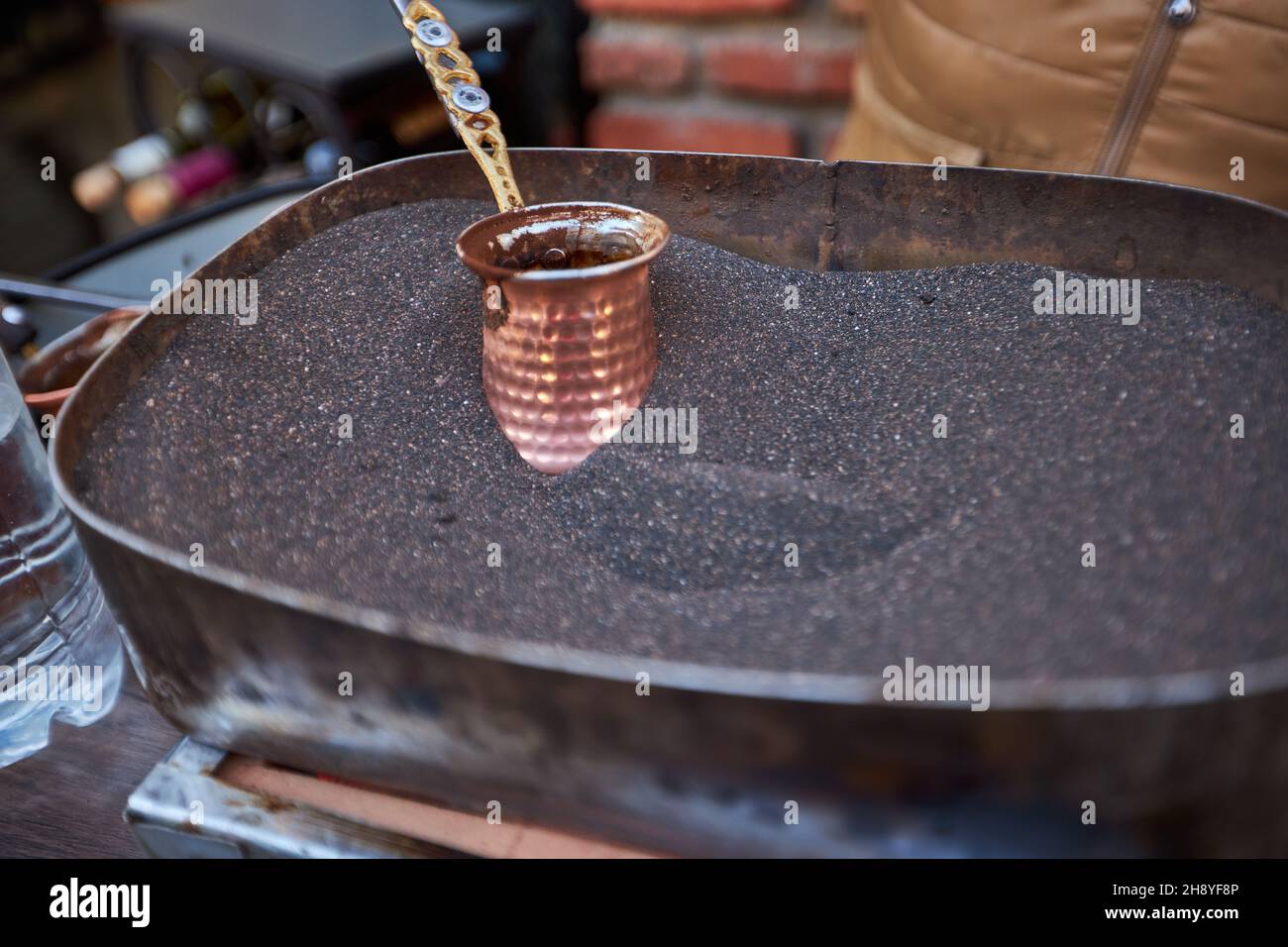 Aromatischer Kaffee, der in heißem Sand gebrüht wird - türkischer Kaffee, der in Cezve braut Stockfoto
