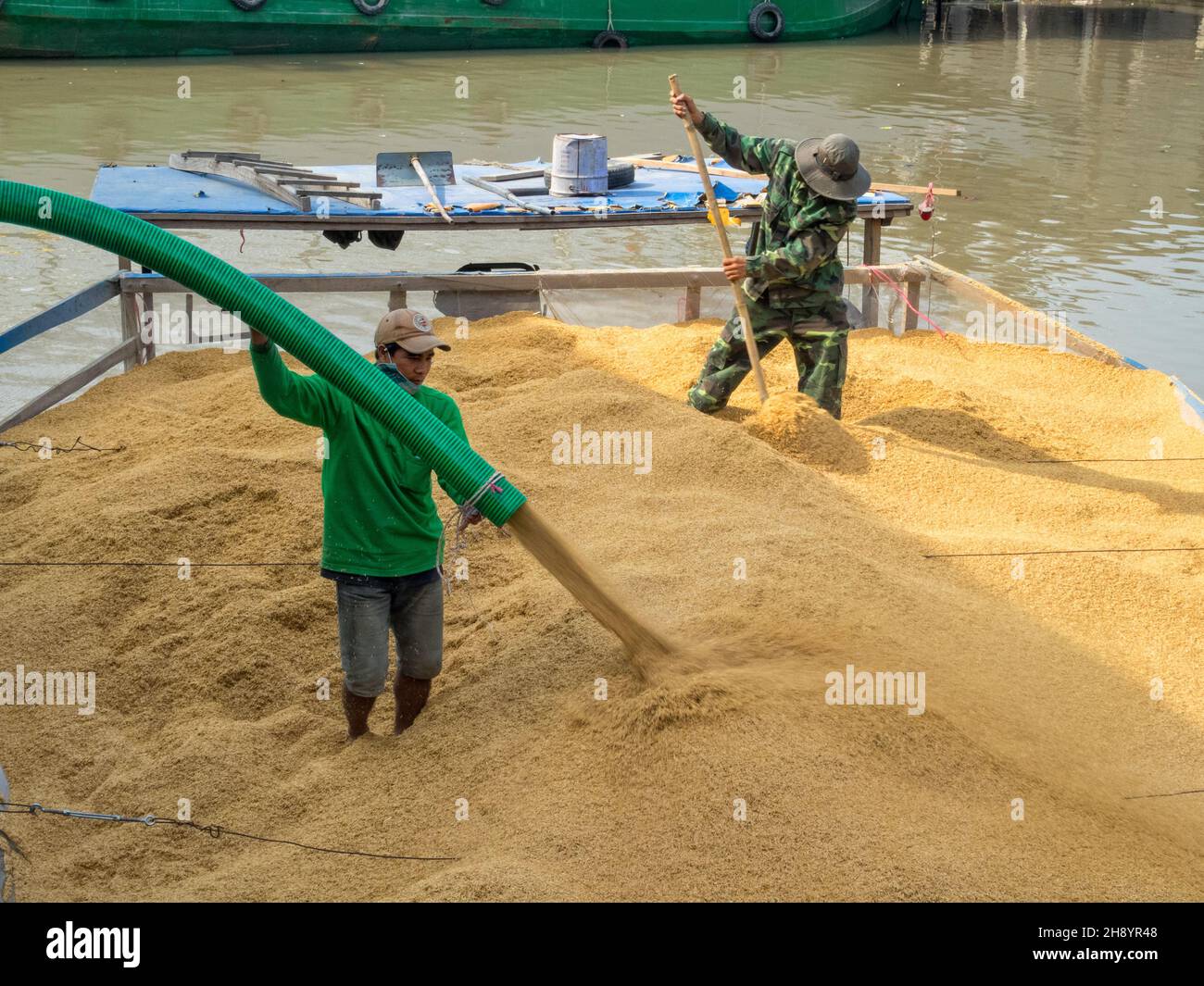 Zwei Arbeiter laden Reis auf ein Boot im Mekong-Flussdelta - Phong Dien, Vietnam Stockfoto