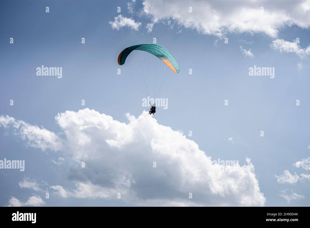 Gleitschirmfliegen mit einem Paar Instruktoren. Strahlend blauer Himmel mit schönen weißen, flauschigen Wolken. Freizeit mit aktiven Abenteuern. Tourismus in Georgien Stockfoto