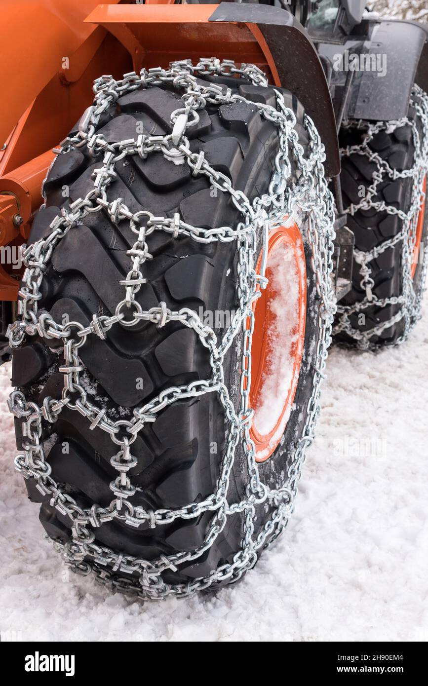 Schneeketten aus Metall, die an den Reifen von Industriemaschinen an kalten Wintertagen befestigt sind Stockfoto