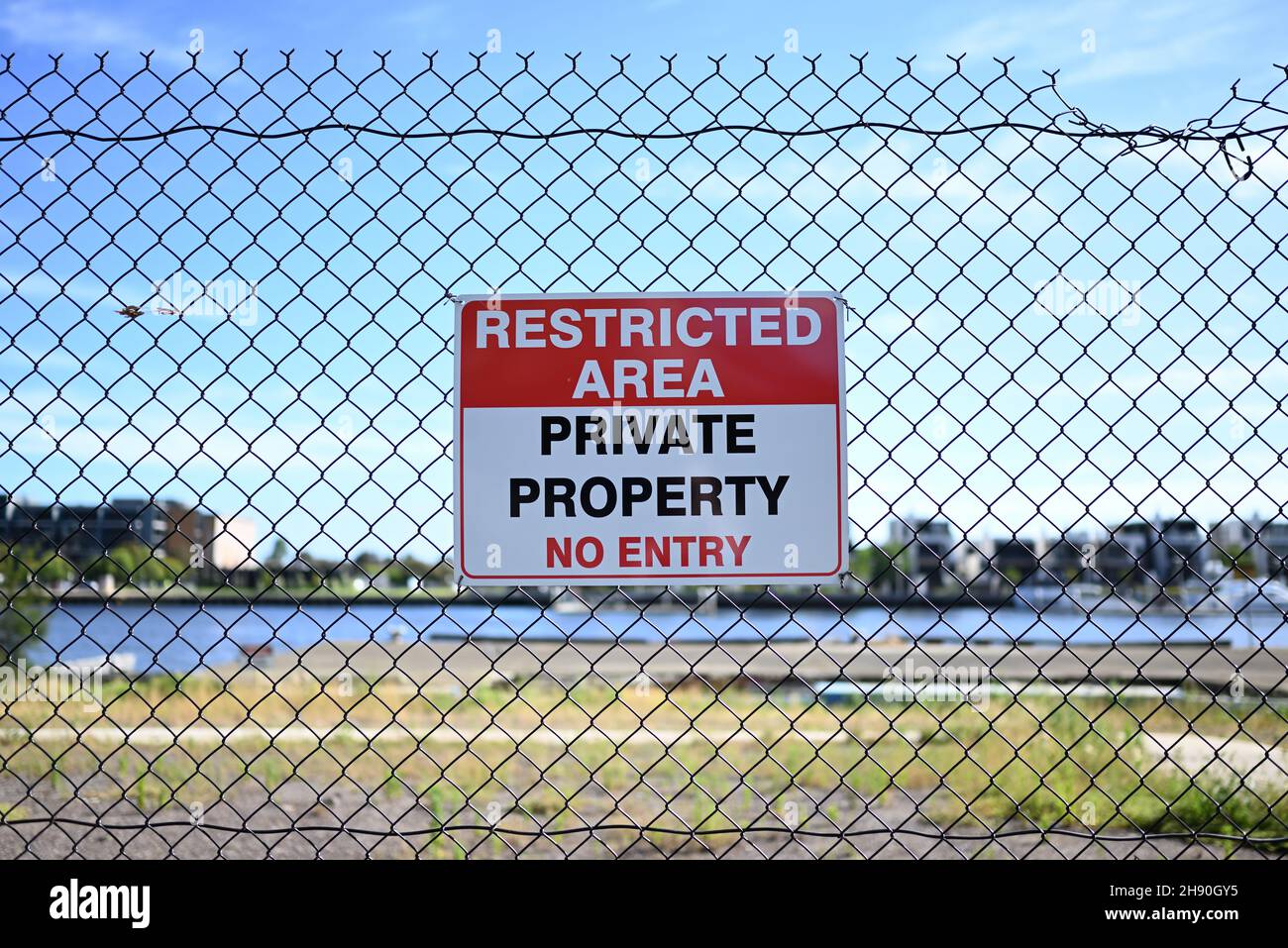Ein Schild mit beschränkter Fläche, das signalisiert, dass sich hinter dem Zaun Privateigentum befindet und dass kein Zutritt erlaubt ist, auf einem Zaun Stockfoto