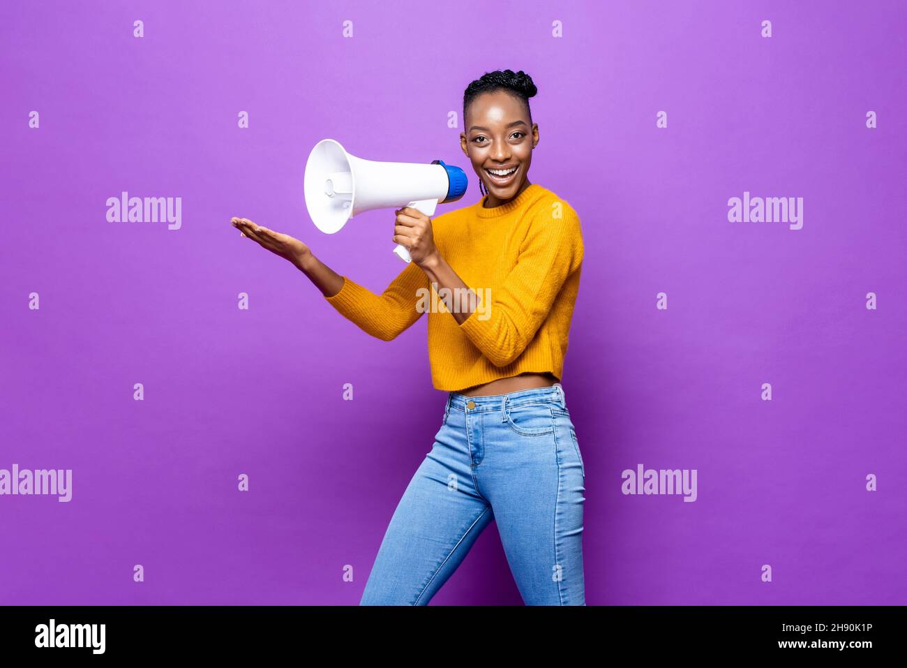 Porträt einer afroamerikanischen Frau, die ein Megaphon hält und die Hand in einem isolierten violetten Studiohintergrund öffnet Stockfoto