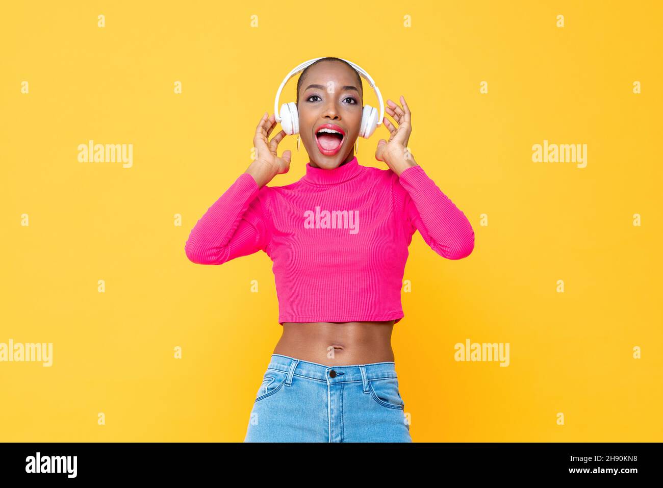 Überrascht afroamerikanische Frau trägt Kopfhörer in gelben Farbe isoliert Hintergrund Stockfoto