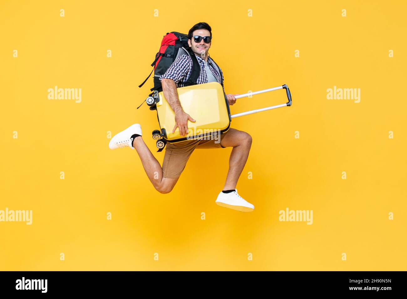 Porträt eines jungen aufgeregten kaukasischen männlichen Touristen mit Gepäck springen in der Luft isoliert auf bunten Studio gelben Hintergrund Stockfoto Porträt eines jungen aufgeregten kaukasischen männlichen Touristen mit Gepäck springen in der Luft isoliert auf bunten Studio gelben Hintergrund Stockfoto