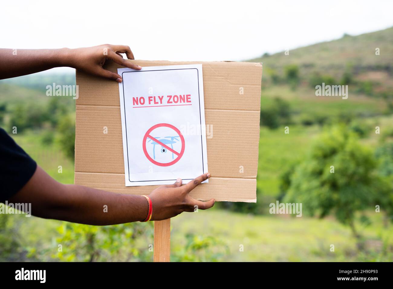 Nahaufnahme der Hände, die als Sicherheitsbestimmungen an Bord des Drohnenverbotsbereichs ein Schild ohne Flugzone kleben - Konzept des Drohnenverbotsbereichs. Stockfoto