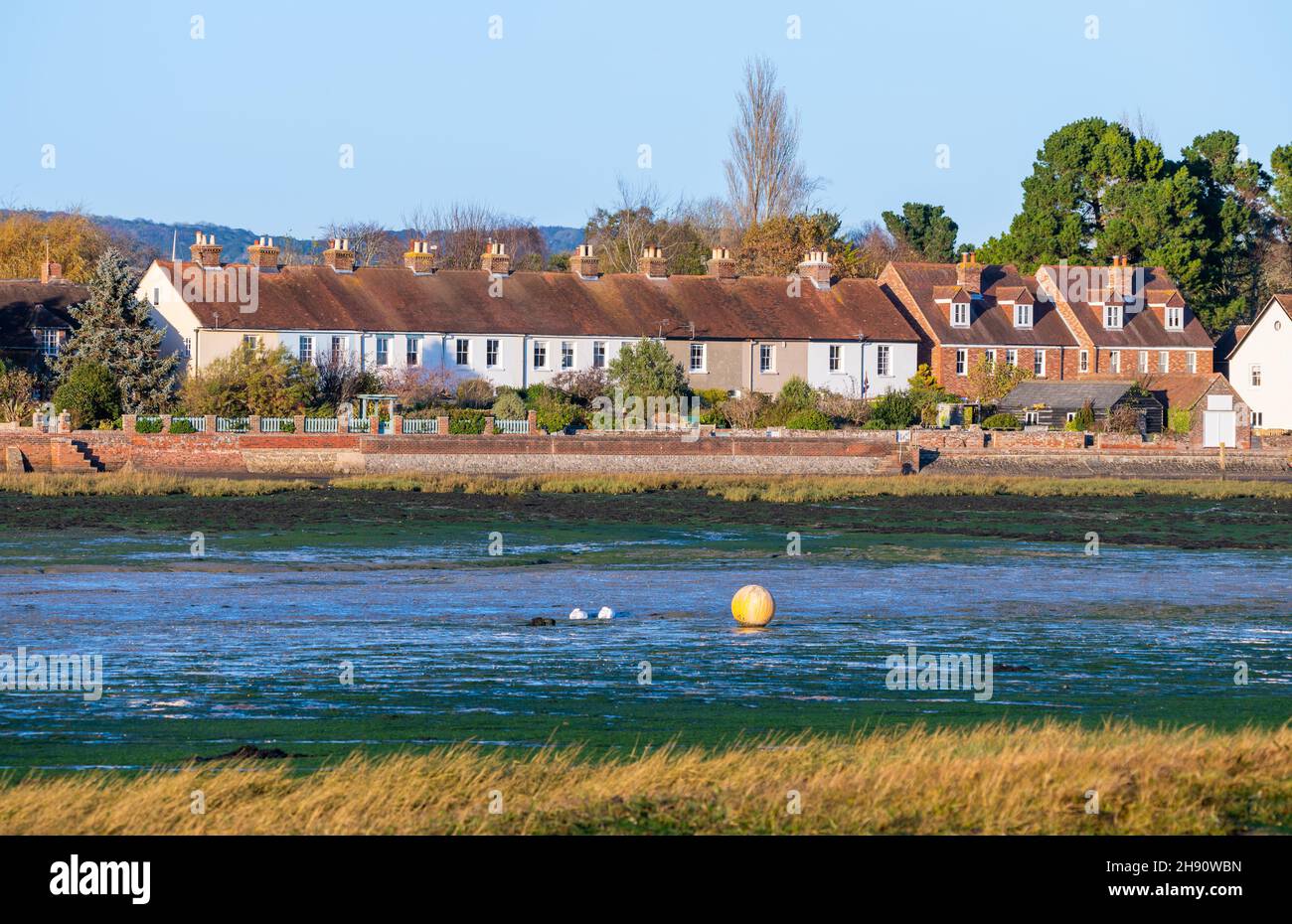 Reihe von Reihenhäusern am Wasser in Bosham Village, Bosham Quay, West Sussex, England, Großbritannien. Stockfoto