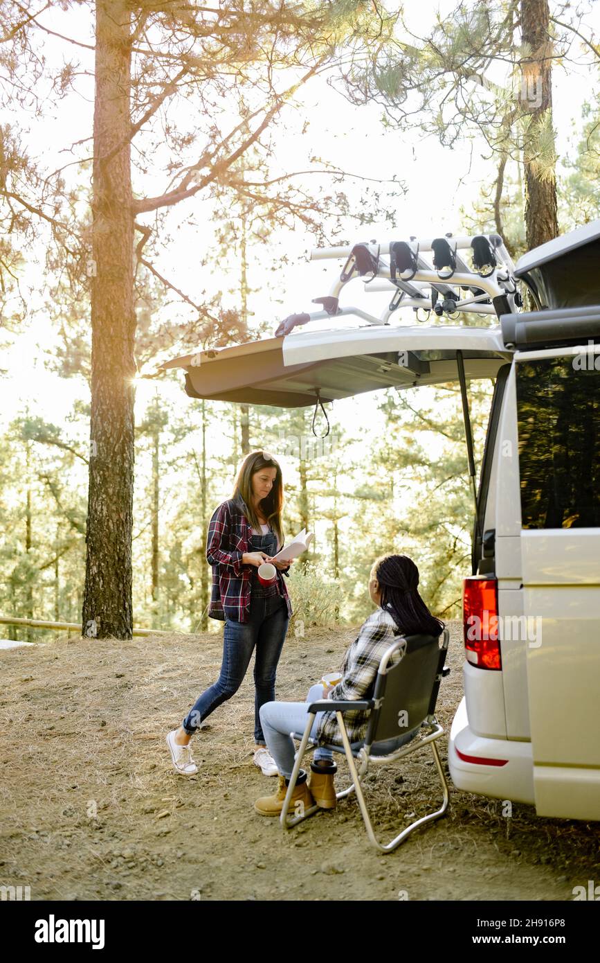 Verschiedene Reisende Frauen in der Nähe Wohnmobil im Wald Stockfoto