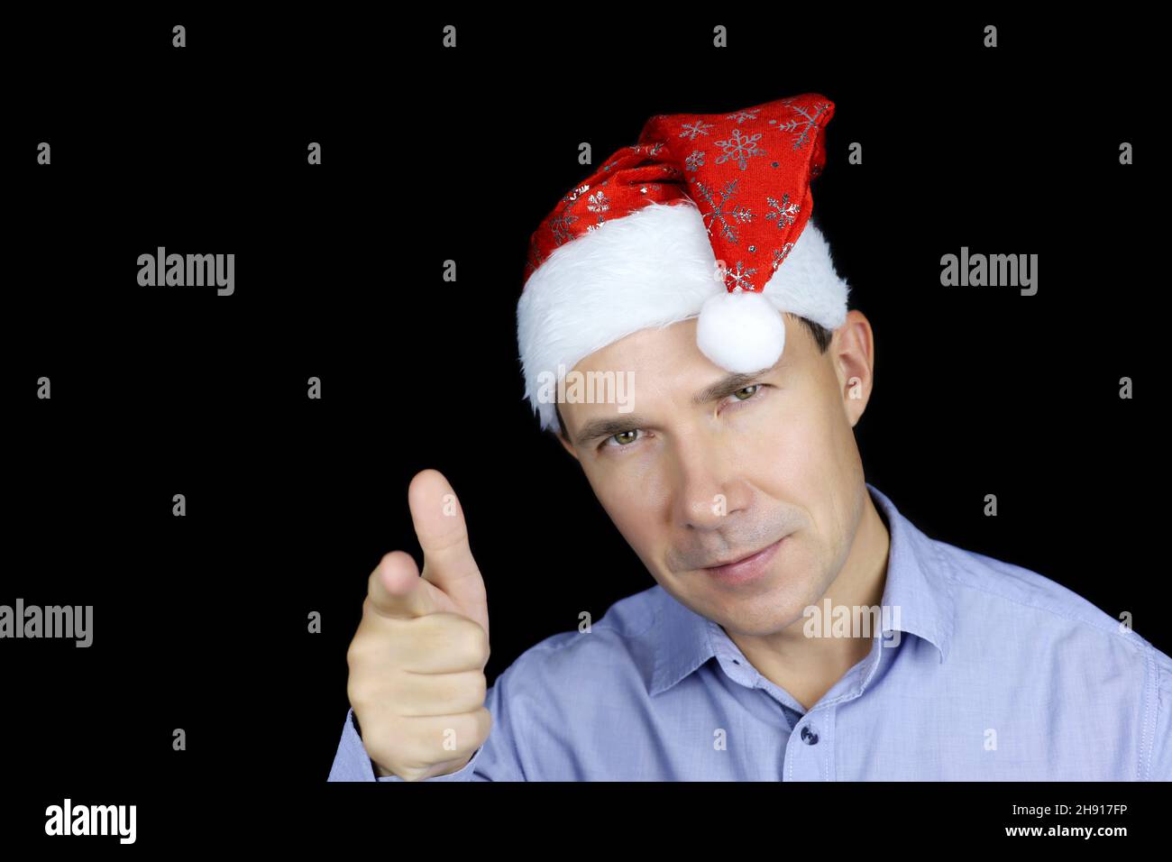 Porträt eines glücklichen Mannes im Weihnachtsmann-Hut, der mit dem Finger auf die Kamera zeigt. Weihnachtsfeier, Neujahrsfeiertag Stockfoto