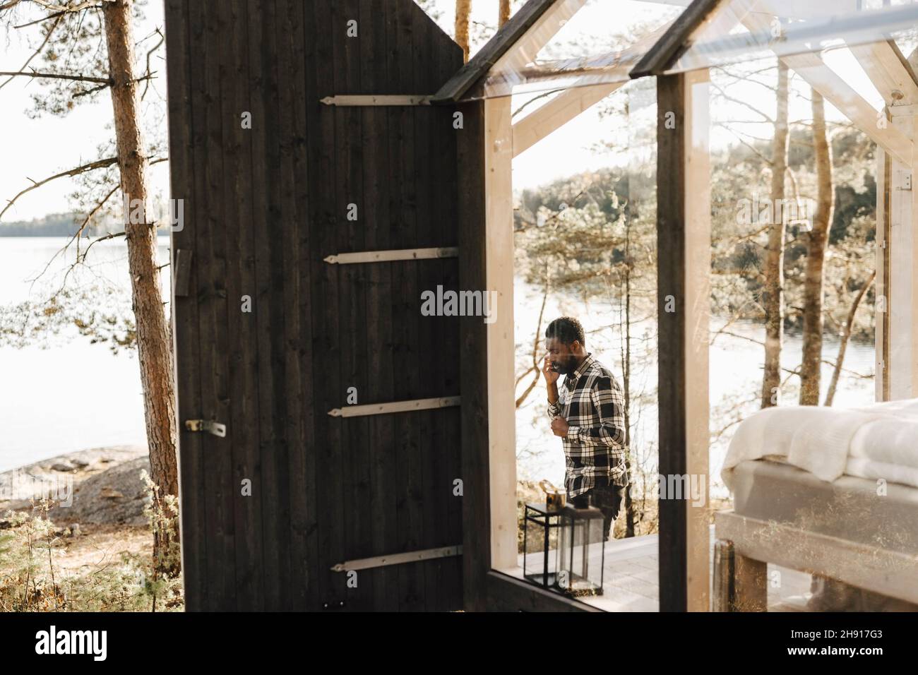Mittelerwachsener Mann, der durch die Hütte im Wald läuft Stockfoto Mittelerwachsener Mann, der durch die Hütte im Wald läuft Stockfoto