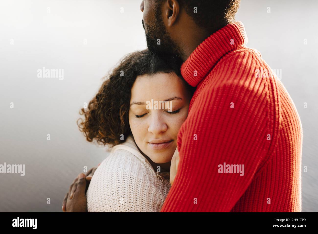 Junge Frau mit geschlossenen Augen umarmt Freund Stockfoto