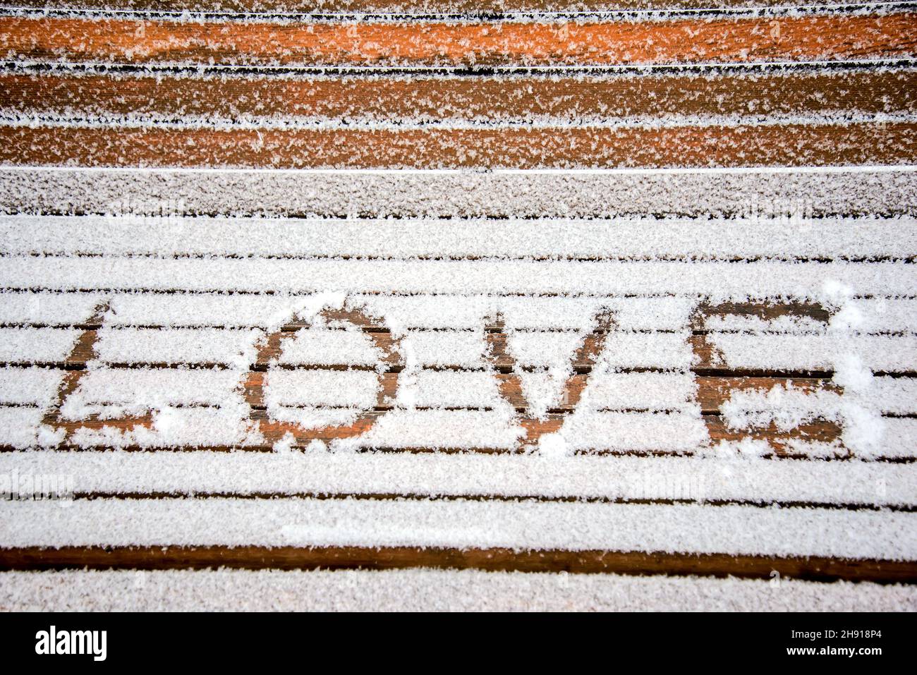 Das Wort LIEBE im Schnee auf einer Bank in einem Winterpark geschrieben Stockfoto