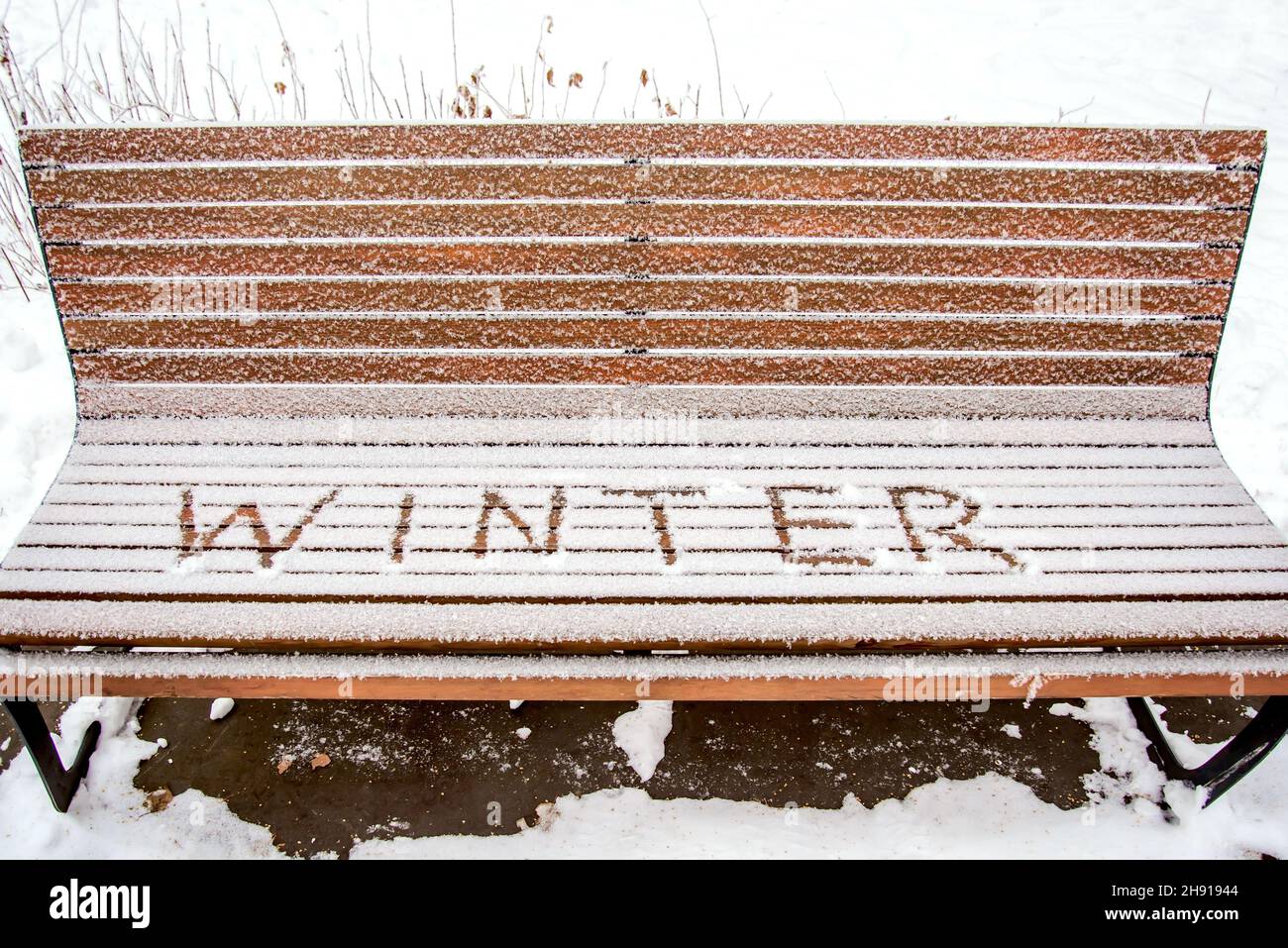 Das Wort WINTER steht im Schnee auf einer Bank im Winterpark Stockfoto