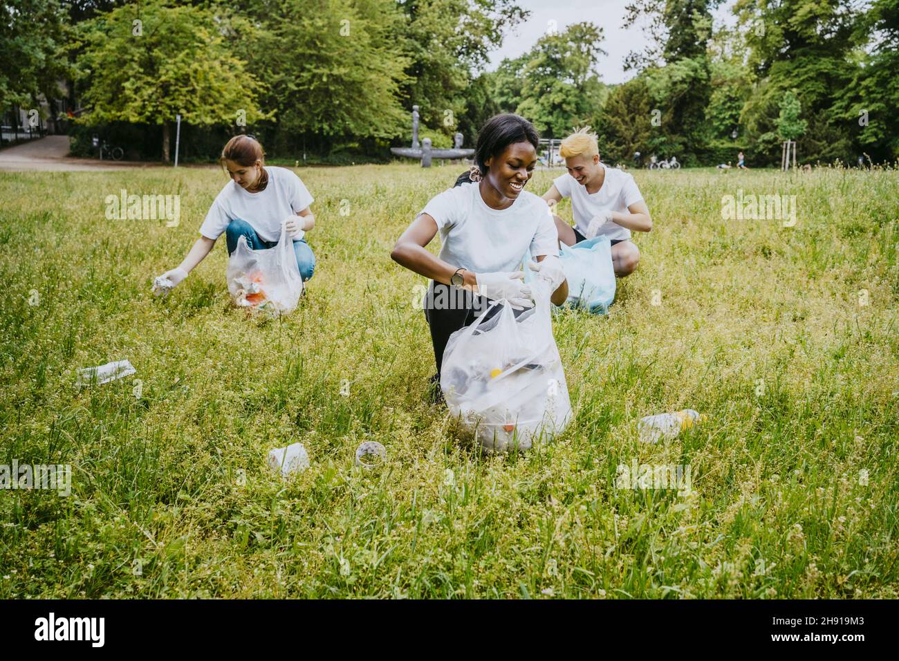 Lächelnde männliche und weibliche Freiwillige, die im Park Plastik abholen Stockfoto