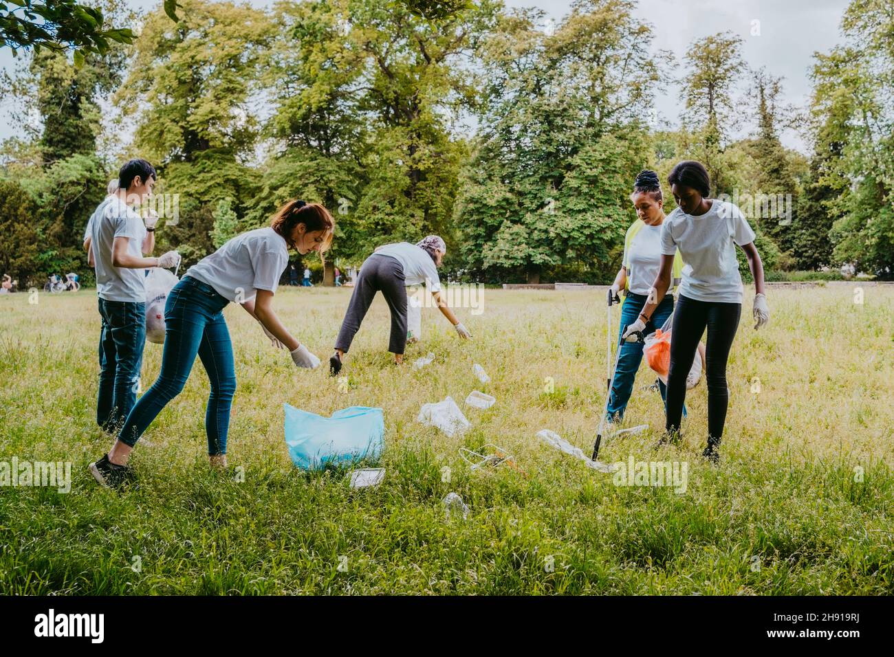 Freiwillige männliche und weibliche Helfer beim Reinigen von Kunststoffen im Park Stockfoto