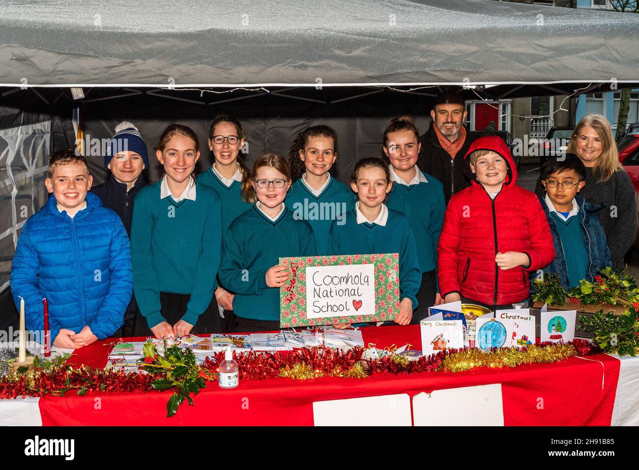 Bantry, West Cork, Irland. 3rd Dez 2021. Der Bantry Farmers Market nahm heute eine Weihnachtsstimmung an. Schüler und Lehrer der Coomhola National School waren auf dem Markt und verkauften handgemachte Weihnachtskarten, Kerzen und Kränze für die 6th-Klassen-Weihnachts-Hoodies. Aus dem Erlös sollen lokale Wohltätigkeitsorganisationen gespendet werden. Lehrer Tom Farmey und SNA Deirdre Kingston sind mit den Schülern abgebildet. Quelle: AG News/Alamy Live News Stockfoto