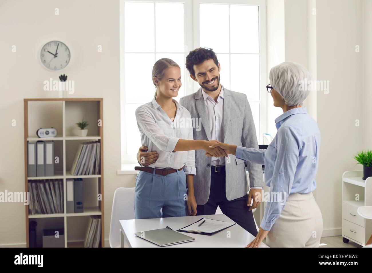 Handshake von Bankkaufmann und junger Familie nach erfolgreicher Unterzeichnung von Dokumenten im Bankbüro. Stockfoto