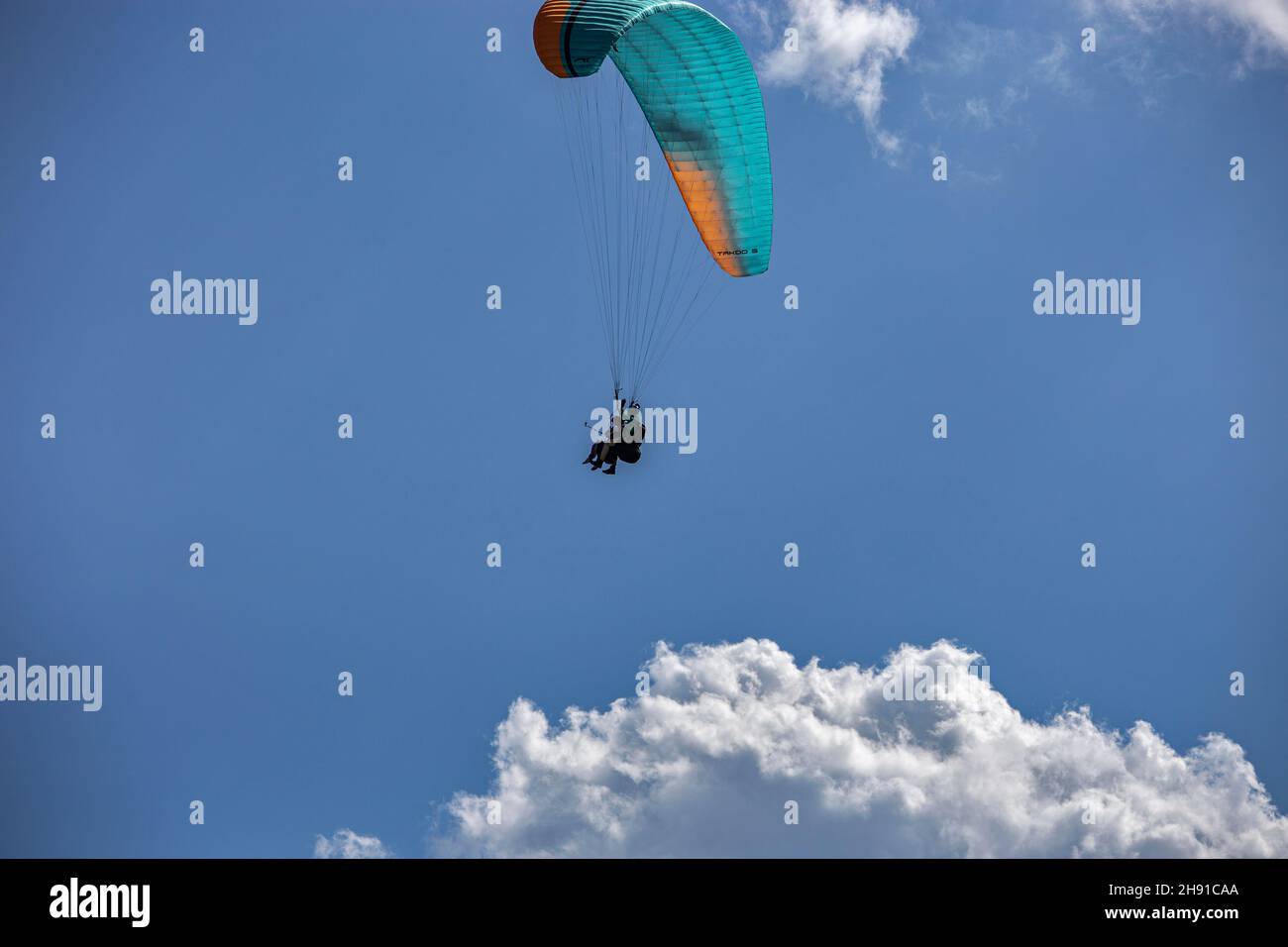 Gleitschirmfliegen mit einem Paar Instruktoren. Strahlend blauer Himmel mit schönen weißen, flauschigen Wolken. Freizeit mit aktiven Abenteuern. Tourismus in Georgien Stockfoto