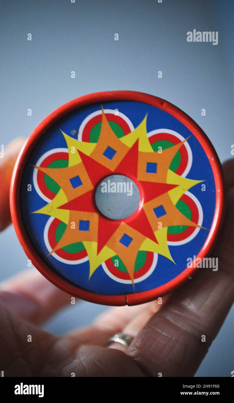 Okular eines Kaleidoskops mit einem hellen bunten Muster. Es wird in der Hand eines Erwachsenen auf einem blassen Hintergrund mit Kopierraum gehalten Stockfoto