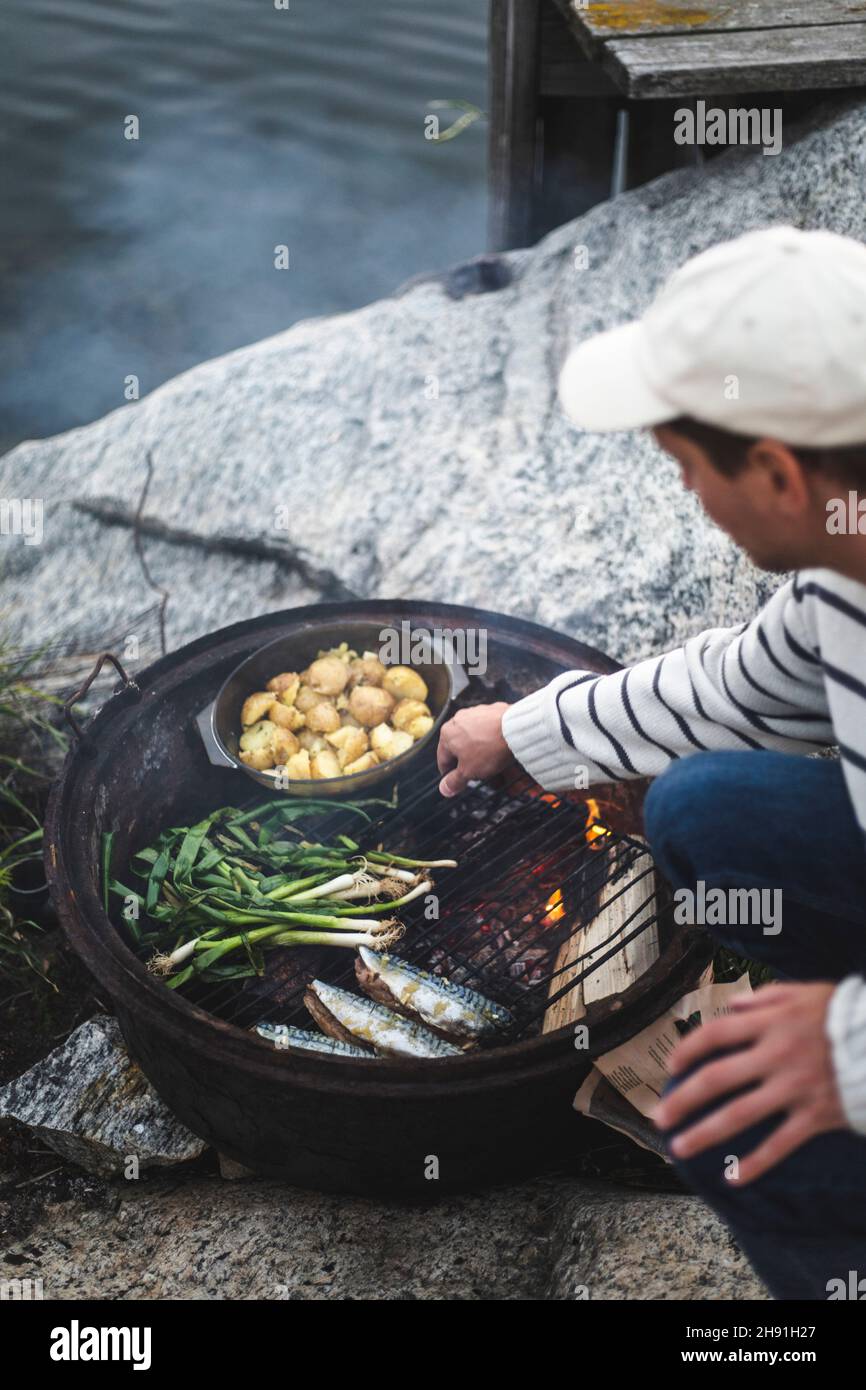 Mittelalter Mann, der auf der Insel Essen auf dem Grill zubereitet Stockfoto