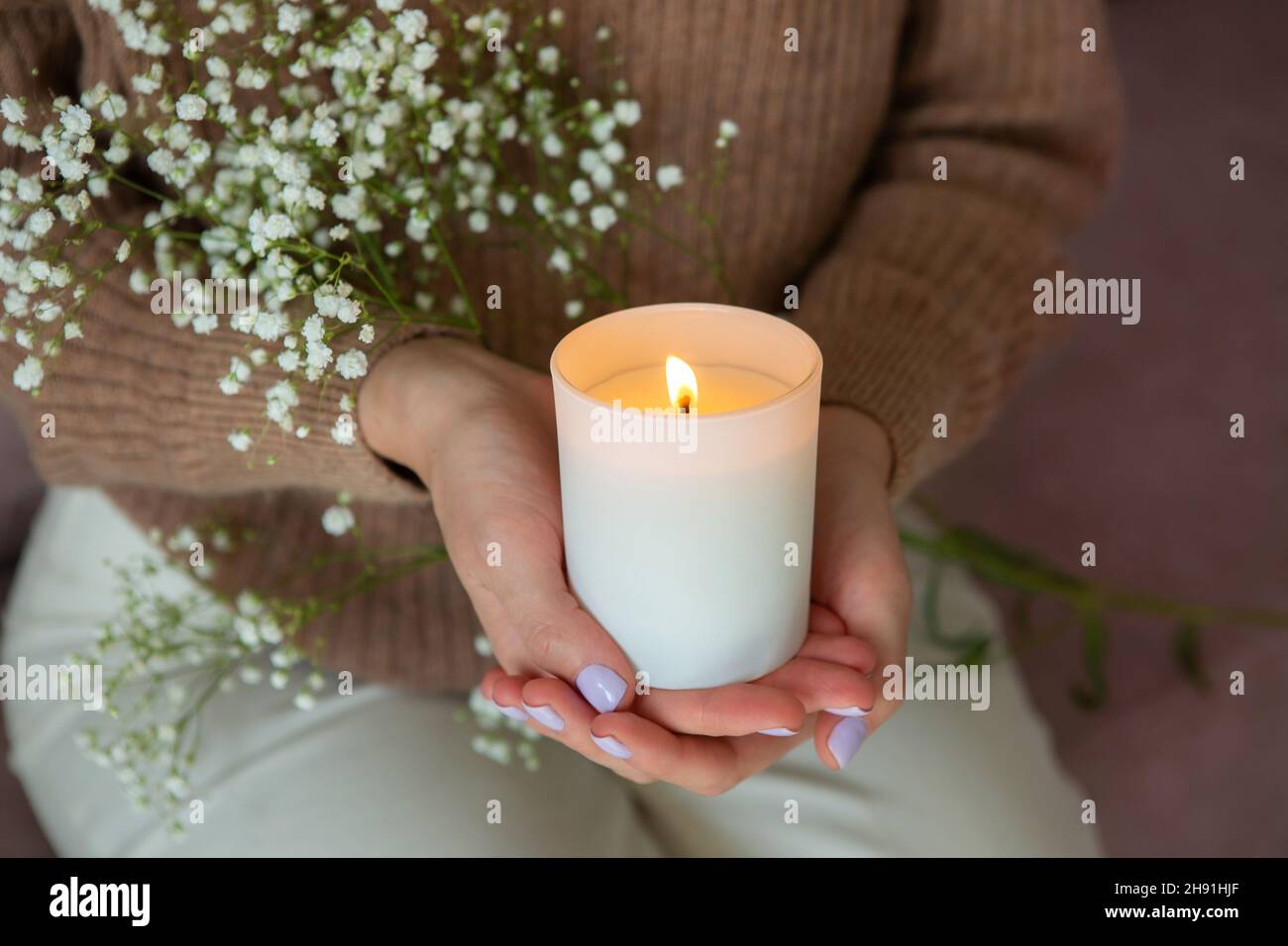 Frau mit brennender Kerze. Hände der Frau und Kerzenschein aus der Nähe. Stockfoto