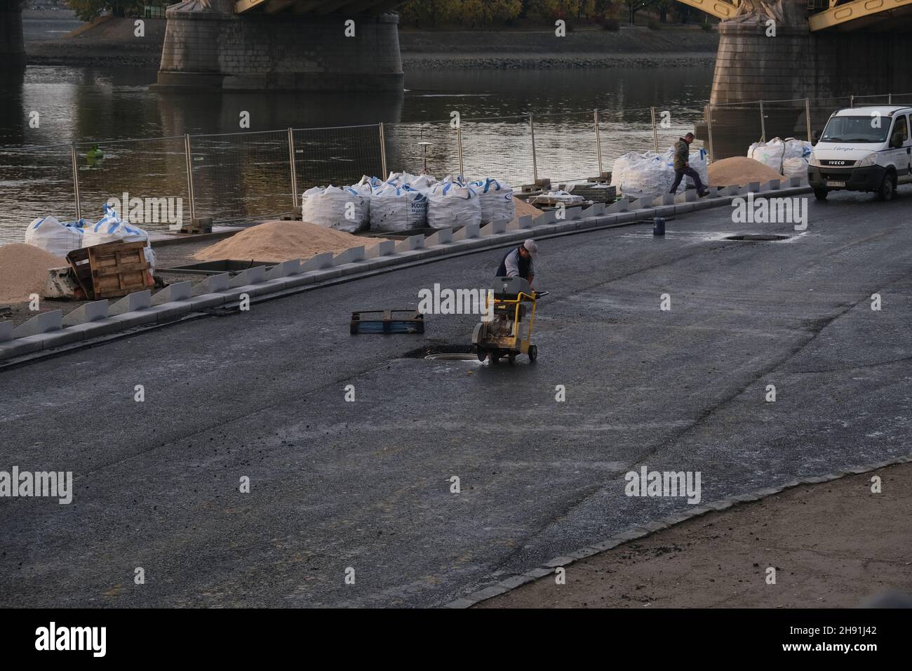 Budapest, Ungarn - 1. November 2021: Arbeiter in einheitlichem Asphalt mit Maschinen auf dem Damm, illustrative Editorial. Stockfoto