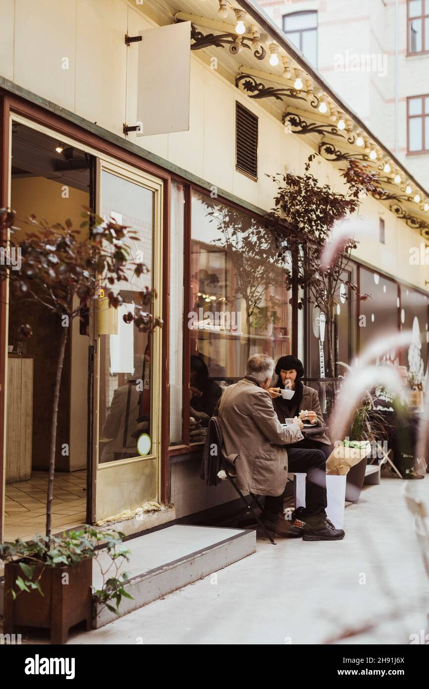 Ein älteres Paar, das Kaffee getrunken hat, während es draußen vor dem Café zusammen saß Stockfoto