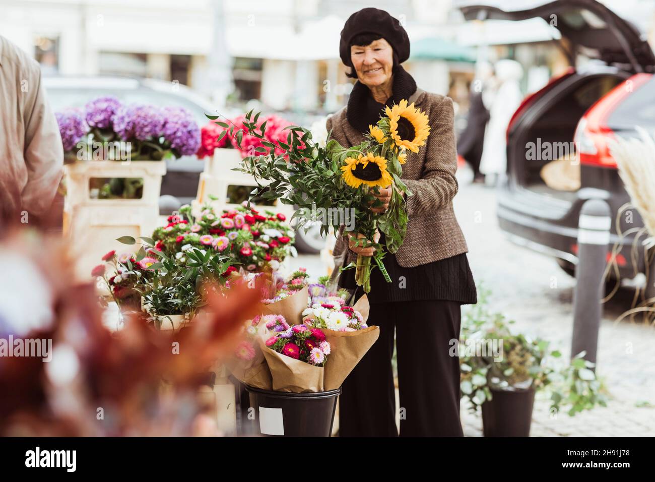 Lächelnde ältere Frau, die Blumen vom Markt kauft Stockfoto