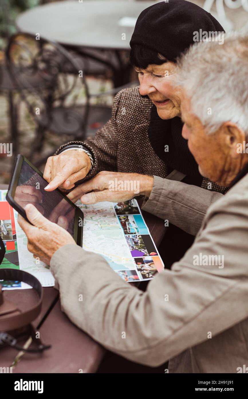 Ältere Männer und Frauen nutzen GPS-Navigation durch digitales Tablet am Tisch Stockfoto