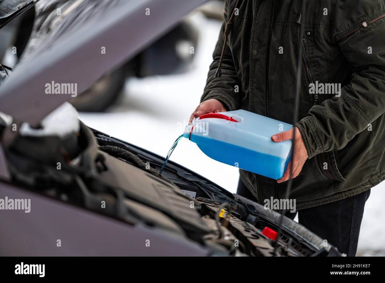 Fahrer befüllen die blaue, nicht gefrierende Scheibenwaschflüssigkeit in den Tank des Fahrzeugs, Nahaufnahme Stockfoto