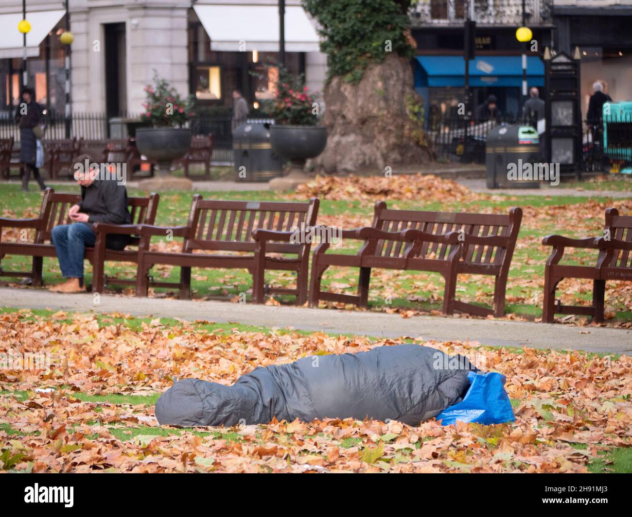 Reiche Arme teilen Ungleichheit, Obdachlose, die auf dem Berkeley Square Mayfair schlafen, gehen unter eisigen Bedingungen unter Herbstlaub, während Büroangestellte vorbei gehen Stockfoto Reiche Arme teilen Ungleichheit, Obdachlose, die auf dem Berkeley Square Mayfair schlafen, gehen unter eisigen Bedingungen unter Herbstlaub, während Büroangestellte vorbei gehen Stockfoto