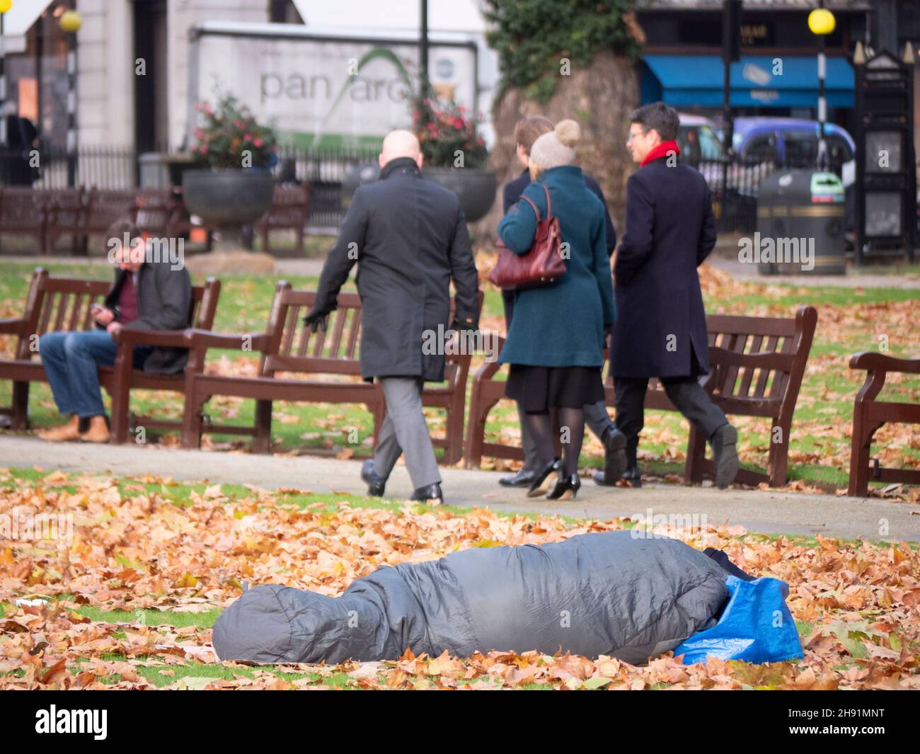 Reiche Arme teilen Ungleichheit, Obdachlose, die auf dem Berkeley Square Mayfair schlafen, gehen unter eisigen Bedingungen unter Herbstlaub, während Büroangestellte vorbei gehen Stockfoto Reiche Arme teilen Ungleichheit, Obdachlose, die auf dem Berkeley Square Mayfair schlafen, gehen unter eisigen Bedingungen unter Herbstlaub, während Büroangestellte vorbei gehen Stockfoto