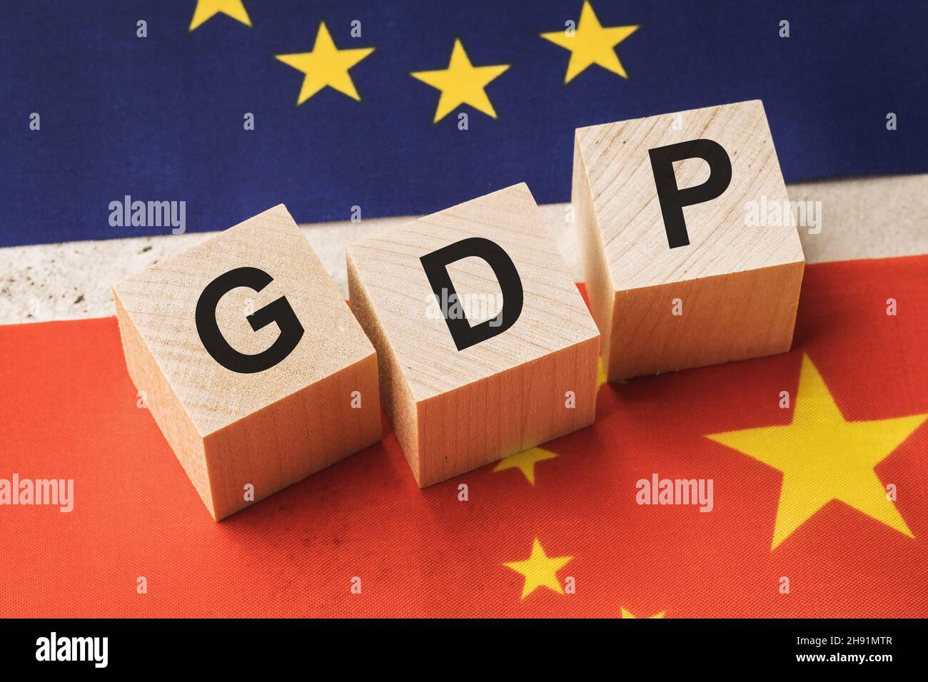 Holzwürfel mit dem Text auf dem Hintergrund der Flaggen, das Konzept zum Thema des Vergleichs des BIP der Europäischen Union mit China Stockfoto