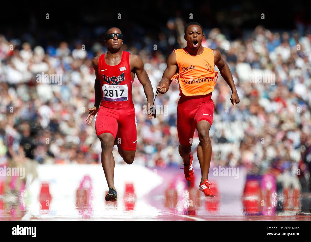 LONDON, England - 7. SEPTEMBER: David Brown mit Führer Rolland Slade (USA) scheint auf Wasserhitze zu laufen und läuft in der 100m T11-Runde der Männer 1 am 9. Tag der Paralympischen Spiele 2012 in London im Olympiastadion am 7. September 2012 in London, England. Foto von Paul Cunningham Stockfoto