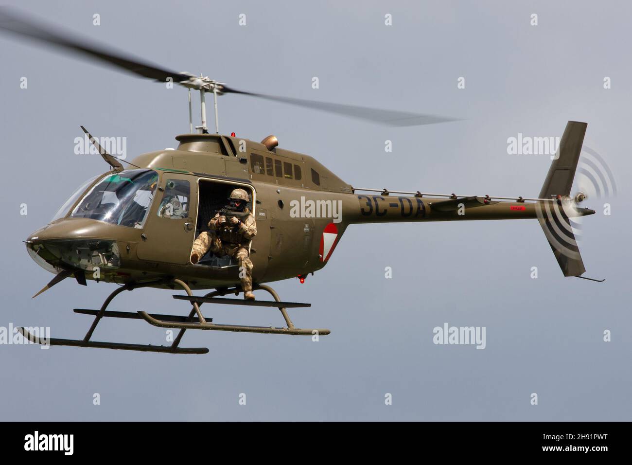 ALLENTSTEIG, ÖSTERREICH - 10. Jul 2013: Der Bell OH-58-Angriffshubschrauber der Österreichischen Luftwaffe mit Türbeschützer in der Luft während eines Kampftrainings in Allentste Stockfoto