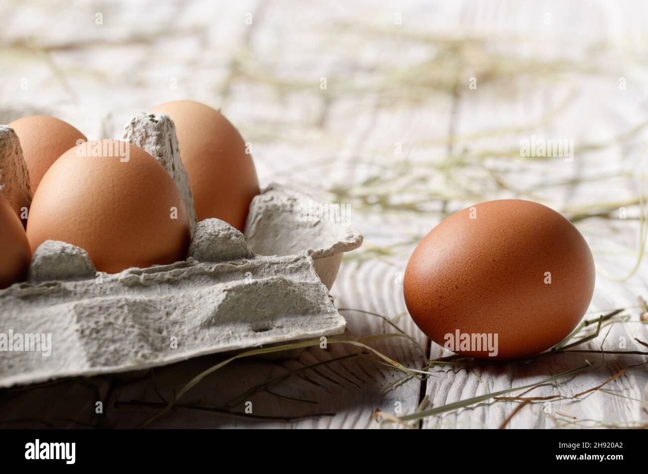 Raw organic Braun huhn eier in umweltfreundliches Papier Karton auf weißen Küche Holztisch Stockfoto